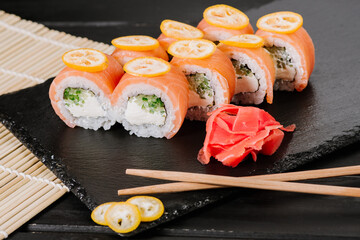 Tasty sushi rolls with salmon on black background