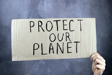 hands holding a cardboard poster with an inscription save our planet