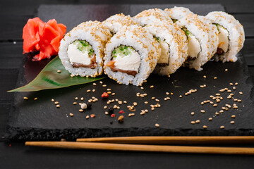 Fresh and tasty sushi rolls on black background