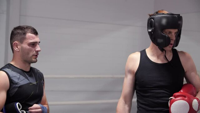 Two fighters analyzing combat duel on boxing ring. Male boxer talking about training in fight club. Kickboxers preparing to fighting on competition