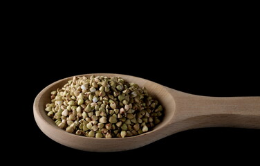 Buckwheat pile with wooden spoon isolated on black background, clipping path