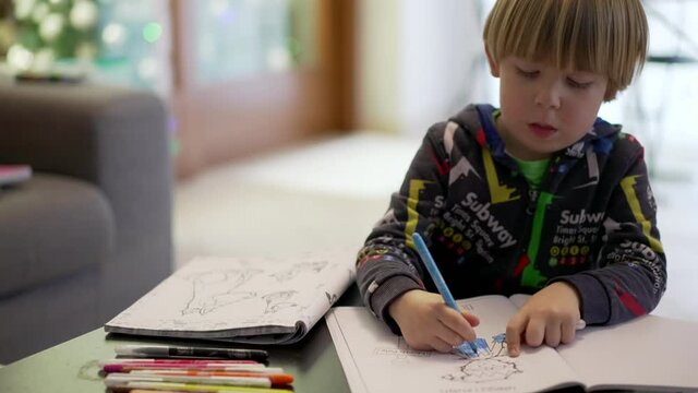slow motion shot of a child paints a coloring book. tracking shot