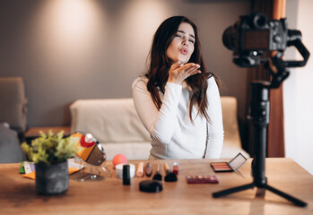 Beauty blogger nice female filming daily make-up routine tutorial on camera. Influencer young woman live streaming cosmetics product review in home studio. Vlogger job. DIY putting makeup