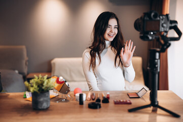 Beauty blogger nice female filming daily make-up routine tutorial on camera. Influencer young woman live streaming cosmetics product review in home studio. Vlogger job. DIY putting makeup