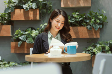 Happy young businesswoman reading a book at the cafe