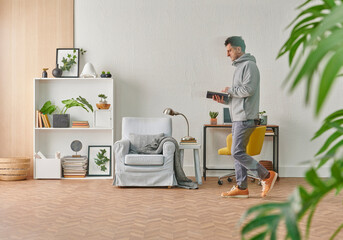 Man is reading a book in the decorative room concept, grey stone wall bookshelf and working table with computer style.