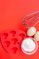 Heart-shaped holiday cupcake ingredients. Red background with empty space. Valentine's Day.