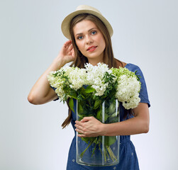 woman holding big glass vase with flowers.