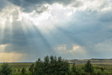  the sun's rays  from behind gray clouds