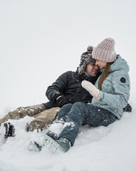 Fototapeta na wymiar Loving guy and girl are lieing in the snow. Young happy couple walking in winter