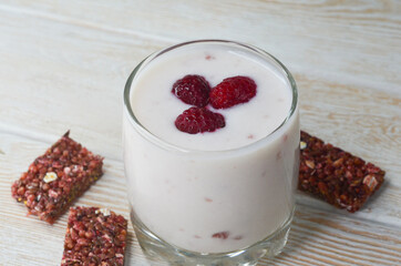 Hearty snack and healthy breakfast glass with homemade yogurt and raspberries and a cereal bar