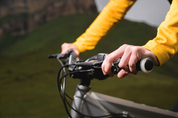 Fototapeta na wymiar Close-up of female hands holding the handlebars of a mountain bike in the summer in the mountains