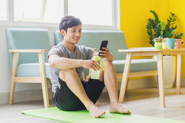 Asian man resting and using phone after exercising