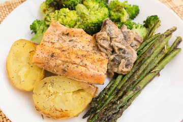 delicious dish of fried river trout fillet with garnish of broccoli, asparagus sprouts, baked potatoes and mushroom sauce