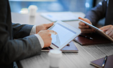 business partners with digital tablets discussing a new contract .