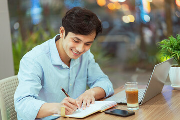 Asian man sitting working alone at a coffee shop