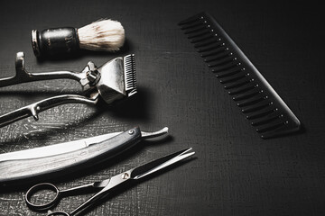 On a black surface are vintage manual barber tools.