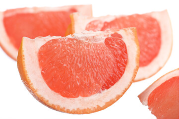 four juicy, fresh grapefruit slices on a white isolated background
