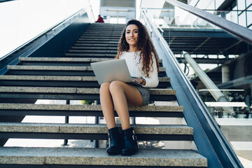 Content woman with laptop on stairs