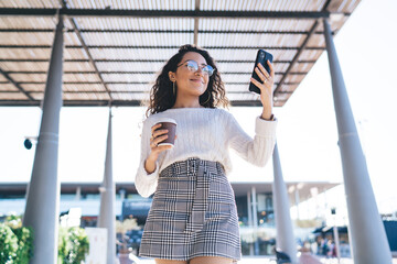 Smiling young student using mobile phone while having break