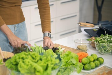 Asian woman preparing vegetables on cutting board to make healthy food salad in modern kitchen room