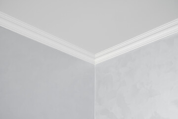 White ceiling with a white plinth in a room with gray painted walls. Decoration of the corner...