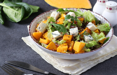 Salad with quinoa, pumpkin and Dor Blue cheese in a plate on a dark background. Close-up