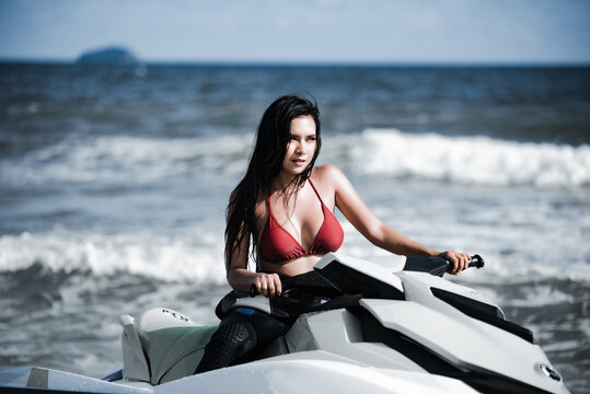 Asian female in bikini sitting on jet ski.