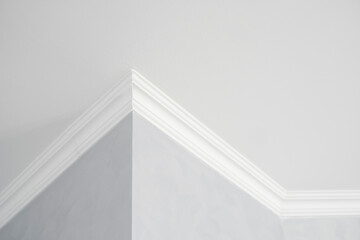 White ceiling with a white plinth in a room with gray painted walls. Decoration of the corner...