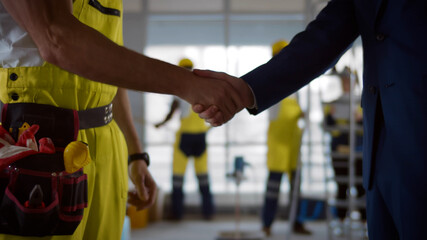 Close up of businessman and builder signing document and shaking hands