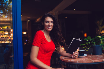Fototapeta na wymiar Young ethnic woman in casual wear with book in cafe