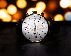White face wristwatch with gold accents on orange bokeh background 