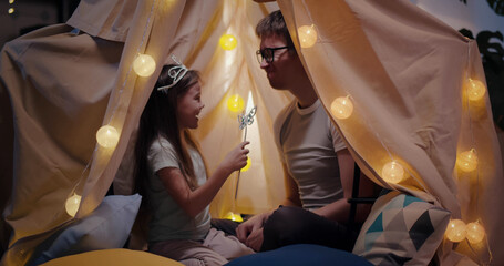Happy father and daughter playing in toy wigwam and having fun © TommyStockProject