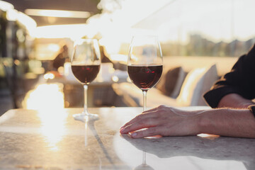 Two glasses of red wine on a sunny fancy restaurant terrace. Marble tables, cosy couch, sunset light, rooftop 