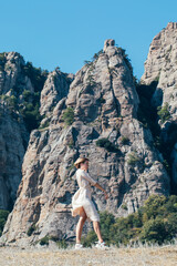 Young woman in safari dress on the rocks in the mountains