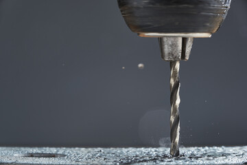 Metal drilling closeup in metal workshop on gray background. Hole being drilled into metal.