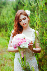 Outdoor portrait of young redhead woman in vintage wedding dress with big bouquet of pink peonies. Woman's Day. Female spring, summer fashion concept. Wedding day.