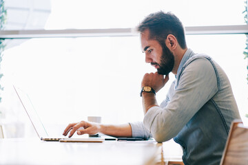 Obraz premium Focused male freelancer using laptop while working