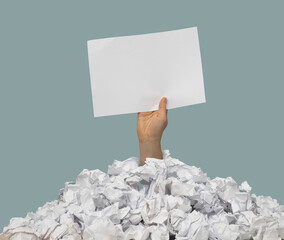 Hand schaut aus Papierhaufen und hält Schild in die Luft