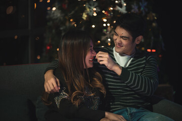 Having fun together at a christmas fairy. Young cheerful couple is dinning and spent time together with enjoying, dressed warm, looking at each other and laugh