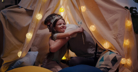 Happy father and little daughter embracing and playing in kids tent