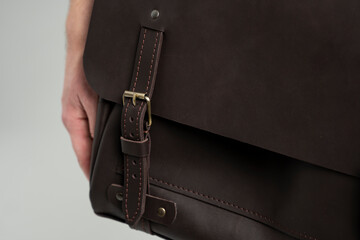 Details of brown men's shoulder leather bag for a documents and laptop on the shoulders of a man in...
