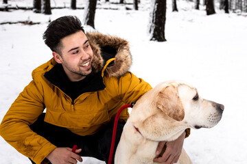 Young man playing with his dog at a snowy mountain