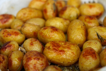 Young potatoes baked in olive oil with rosemary and garlic on parchment paper- close up 