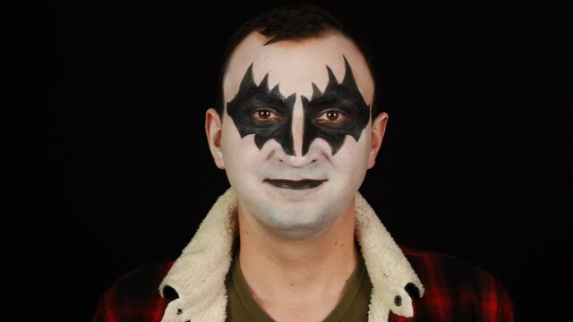 Portrait of happy man in halloween demon makeup on black background