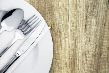 Fork, spoon and knife on a plate on wooden desk