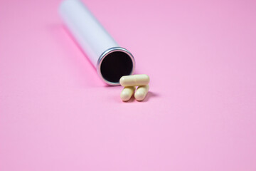 White pills next to a flask on a pink background. Health concept. Health care.