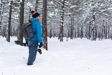 Fototapeta na wymiar Nature photographer walking in a snowy forest.