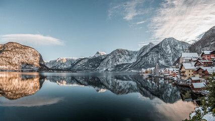 Panorama view of snowy village Hallstatt by lake at foot of snow mountain with clear sky in winter in Austria