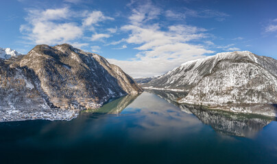 Aerial drone shot of ferry boat on Hallstatt lake surrounded by snow mountains in Austria in winter before sunset time